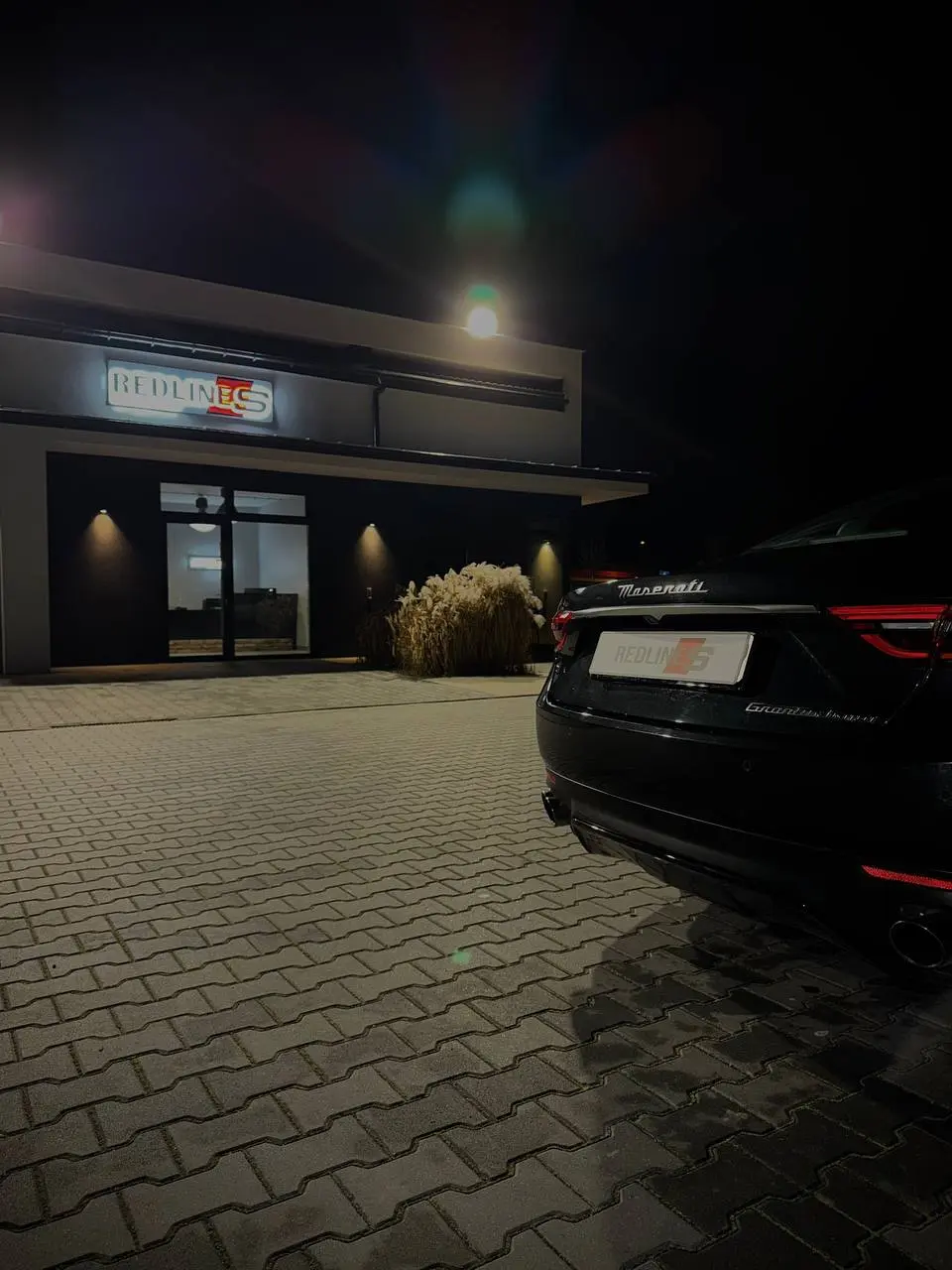 Maserati GranTurismo nocą przed podświetlonym szyldem Redlines