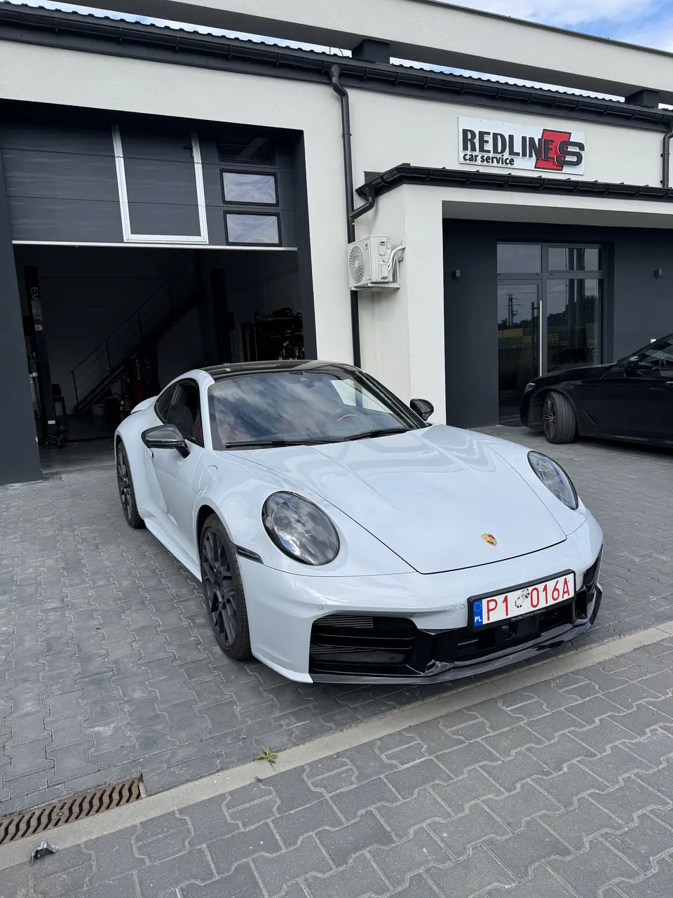 Białe Porsche 911 przed warsztatem Redlines